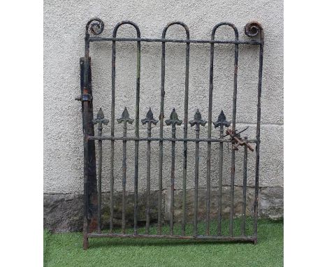 A WROUGHT IRON PEDESTRIAN GATE of multi barred form, the upper bars rounded at the top, the lower with fleur de lys finials, 