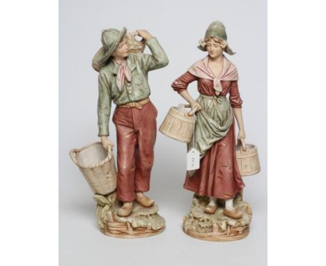 A PAIR OF ROYAL DUX FIGURES, early 20th century, modelled as a young peasant couple wearing typical garb and carrying baskets