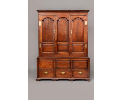 A GEORGIAN JOINED OAK CLOTHES PRESS, mid 18th century, the moulded cornice over a pair of twin arched fielded panel doors fla