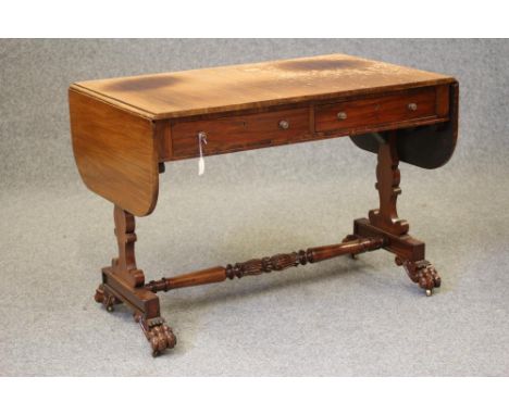 A REGENCY ROSEWOOD SOFA TABLE, the rounded oblong top over frieze with two drawers, with turned brass handles, scrolled silho