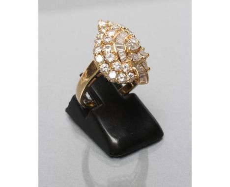 A DIAMOND COCKTAIL RING, the leaf shaped panel variously set with baguette and brilliant cut stones to a plain unmarked shank