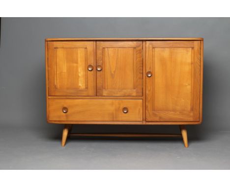 AN ERCOL GOLDEN ELM SIDEBOARD, 1960's, the rounded oblong top over two panelled doors with drawer below flanked by a large cu