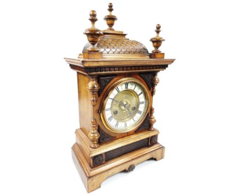 A late 19thC walnut mantel clock, with 13cm dia. Roman numeric dial, with a key wind movement, in a shaped case, surmounted b