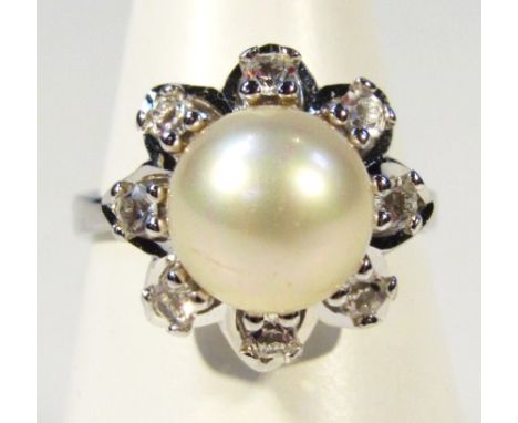 A ladies dress ring, headed by a pearl surrounded by small white stones on a pierced white metal setting, marked 9c, size O, 