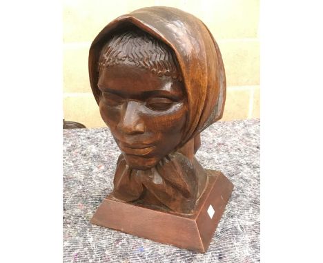 A carved female head bust wearing a scarf, possibly pine, on a square plinth, 39cm high