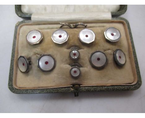 A cased gentleman's dress set, stamped 'silver' with mother of pearl and red paste decoration