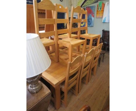 A contemporary light oak extending dining table on legs of square section along with ten conforming ladder back dining chairs