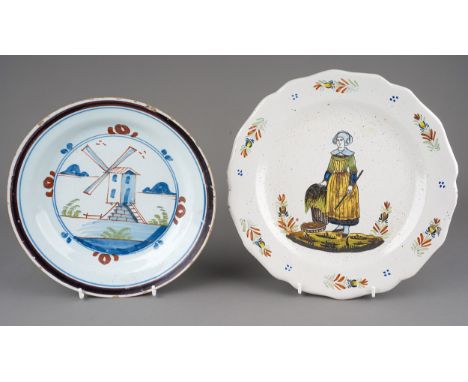 An early 18th Century Delftware dish, the centre painted with a windmill with foliage and rockery within double concentric fr