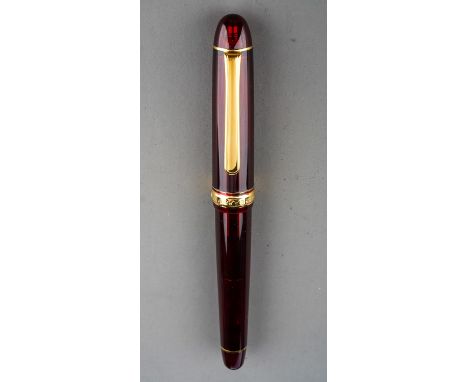 A Japanese Platinum burgundy and gilt transparent fountain pen, the nib stamped #3776 P 14K MUSIC 585, the cover band engrave