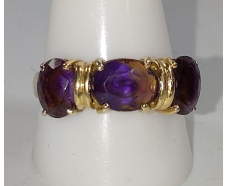 A gold colour metal ring set with three possible amethyst size K. provenance 80 Rose Street Wokingham. 