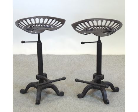 A pair of black painted cast iron tractor seat revolving bar stools