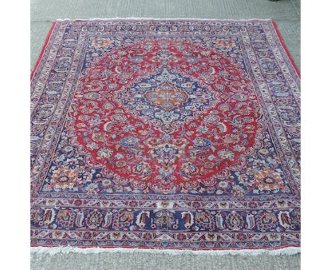 A Persian woollen carpet, with a central medallion and floral designs, on a red ground, 244 x 303cm