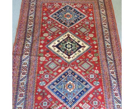 A Shirvan woollen carpet, with three central medallions, on a red ground, 306 x 207cm