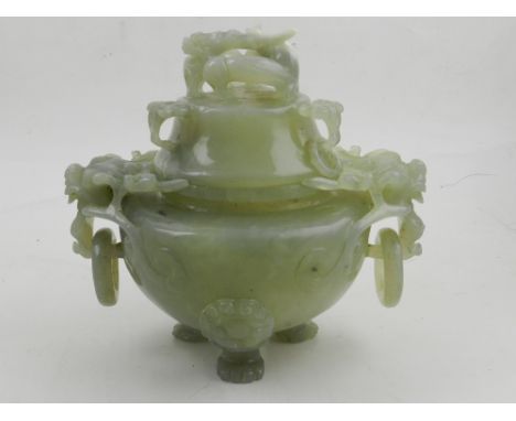 A Chinese carved and pierced celadon jadeite koro and cover, having twin dragon mask handles below a dragon finial, raised on