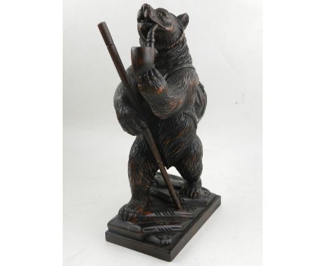 A Black Forest style wooden carving of a bear smoking a pipe.