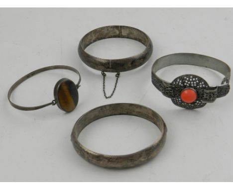 A white metal and tigers eye bangle, together with a filigree white metal and coral bracelet, and two further silver bangles.