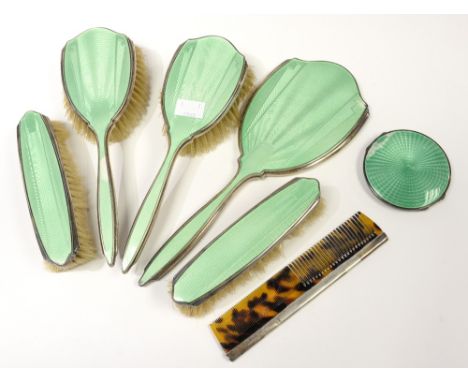 An Art Deco silver and enamel dressing set, the green guilloche enamelled brushes, mirror, compact and comb, fitted in a trav