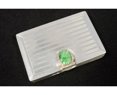 An Art Deco French silver compact, engine turned, striped decoration, the thumbpiece set with a jade carving and diamonds, ma
