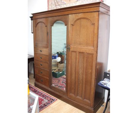 A Liberty Arts and Crafts oak wardrobe, circa 1910, three bays with double doors and drawers, fitted with oxidised ring handl