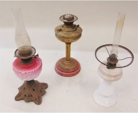 A VICTORIAN OIL LAMP  with pink opaque glass reservoir and cast metal base, another with ceramic base and a white opaque glas