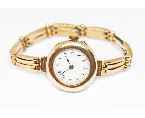 A late Victorian/Edwardian ladies 9ct gold watch and strap, white enamel dial with gold dot minute markers and Arabic numeral