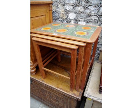 A nest of three teak tables, the largest with tile inset surface, labelled 'Stewart Griffiths Furniture', 54cm wide. 