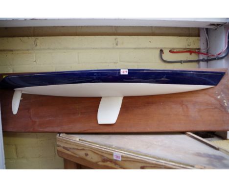 A fibreglass half hull model, on teak plinth, 122cm wide. 