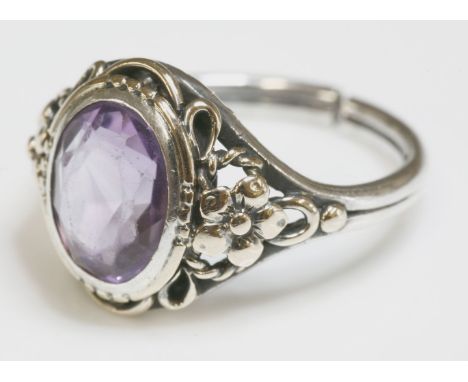 An Arts and Crafts silver and gold amethyst ring,possibly by Bernard Instone, an oval mixed cut amethyst, rub set in silver w