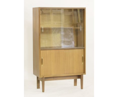 A teak bookcase,designed by Robert Heritage for Beaver & Tapley, with a sliding glass front, enclosing a shelf and a sliding 