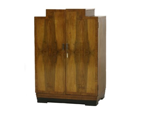 An Art Deco walnut dressing cupboard,of stepped form, enclosing a shelf and three drawers, on stepped bracket feet,75.5cm wid