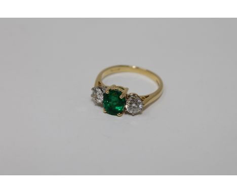 An 18ct gold emerald and diamond three stone ring, size K