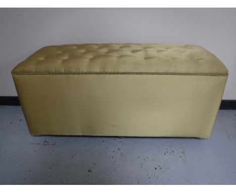 A large blanket box upholstered in a gold button fabric 