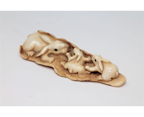 A well-carved Japanese ivory netsuke depicting a family of rabbits, Meiji period, signed to underside, length 8.5cm