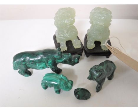 A pair of jade foo dogs on wooden stands, height 6cm, together with four carved green stone animal figures