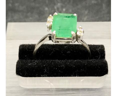 An Emerald ring with diamond shoulders on white gold band marked 750