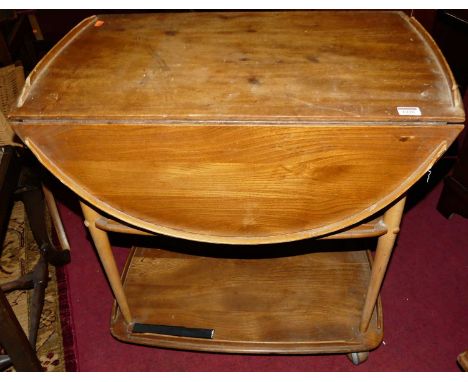An Ercol light elm dropflap three-tier tea trolley, on roller castorsCondition report: Some looses and fading throughout.