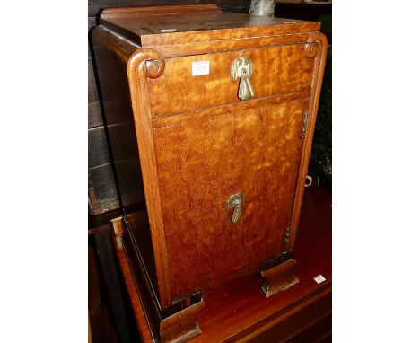 An Art Deco figured walnut single drawer bedside cupboard, having single upper drawer and raised on slightly shaped bracket s