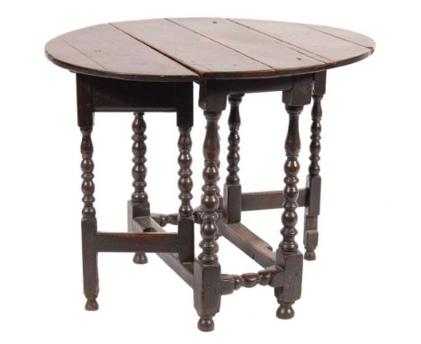 An early 18th Century oak oval gateleg table:, the hinged top on bobbin turned legs, united by plain stretchers, terminating 