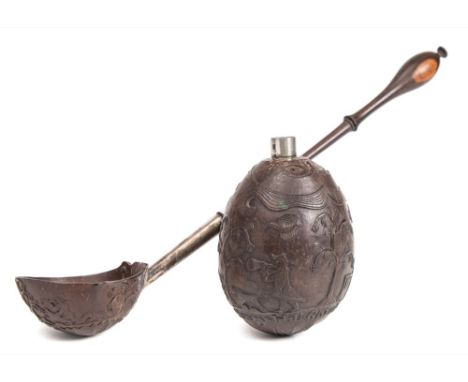 An 18th century white metal mounted and relief carved coconut: with plain cylindrical nozzle as the mouth of a man with mirro