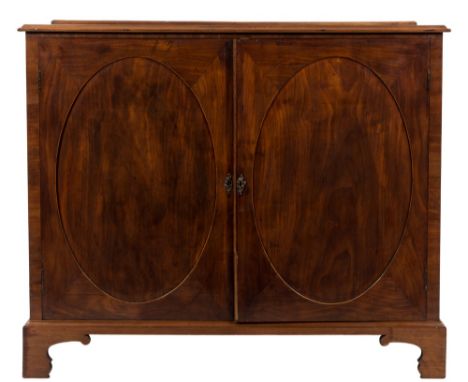 A George III mahogany and inlaid side cupboard:, with a narrow ledge back, fitted with sliding trays enclosed by a pair of re