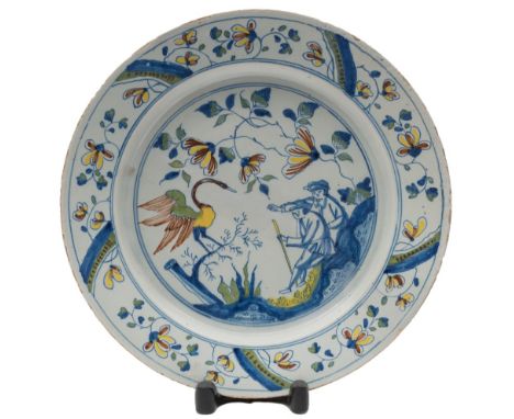 A Bristol polychrome delftware dish: painted with two men seated on rockwork pointing towards a large heron-like bird within 