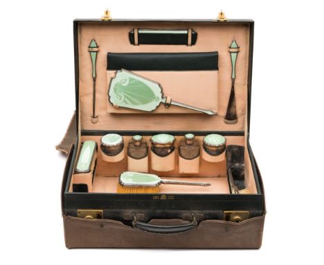 A George V green leather travelling vanity case: containing silver and green enamel mounted jars, bottles, brushes and mirror