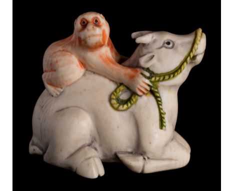 A Japanese carved and stained ivory netsuke: depicting a monkey seated on the back of an oxen, signed Kuwata, 4.25cm. wide.