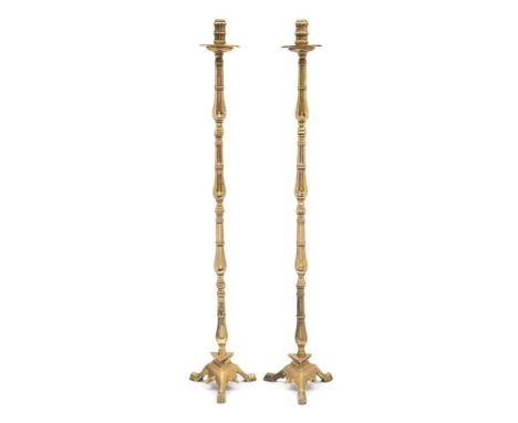 A pair of 19th century brass floor standing candlesticks: with ring turned nozzles, circular drip trays, on slender knopped s