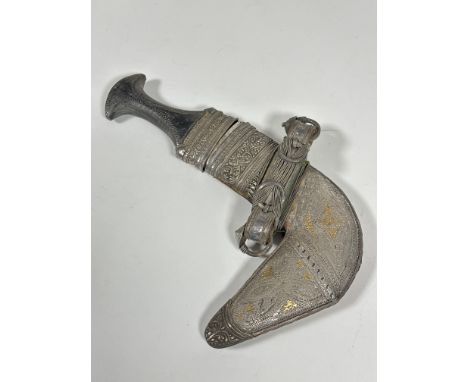 A Omani white metal mounted khanjar, of characteristic form, with shaped horn handle, the scabbard ornately decorated with sc