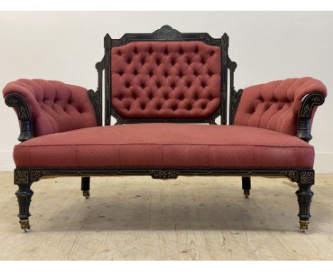 A  Victorian Aesthetic period ebonised drawing room sofa, the show frame inscise carved and parcel gilt enclosing deep button