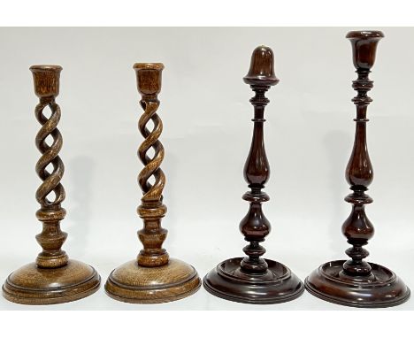 A pair of twist-stem oak candlestick holders (h- 31cm), together with a pair of mahogany candlestick holders (h- 35cm, one br