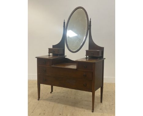 An Edwardian inlaid mahogany dressing chest, fitted with an oval mirror swivelling between square tapered uprights with brass