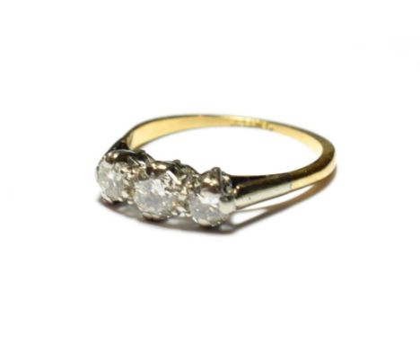 A diamond three stone ring, the graduated round brilliant cut diamonds in white claw settings, to a yellow tapered shoulder p