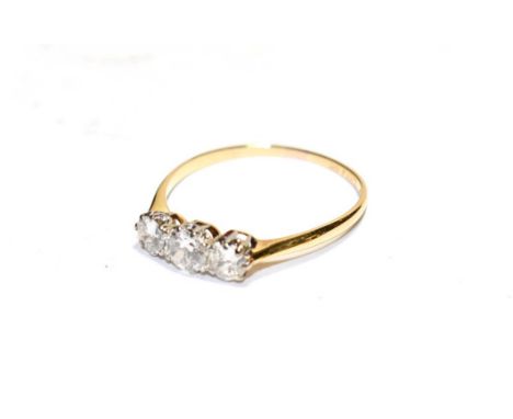 A diamond three stone ring, the graduated round brilliant cut diamonds in white claw settings, to a yellow tapered shoulder p